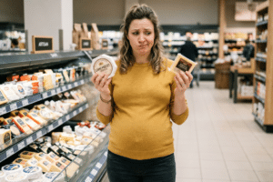 Mujer embarazada eligiendo queso en el supermercado durante el embarazo